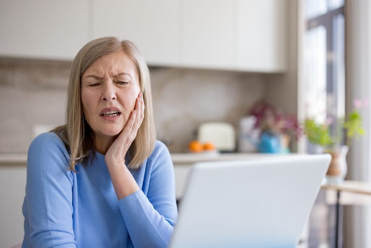Senior woman feeling severe toothache pain holding jaw